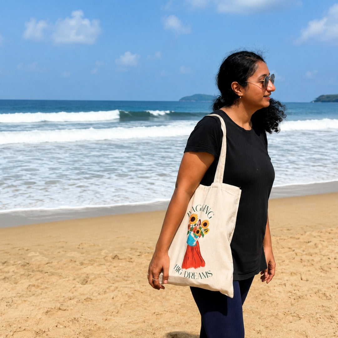Woman holding a tote bag with a design   quote "bagging big dreams" on a beach