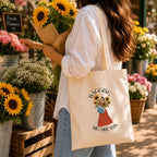 Person holding a The Wonder Whale tote bag with a floral design and text in a flower shop.