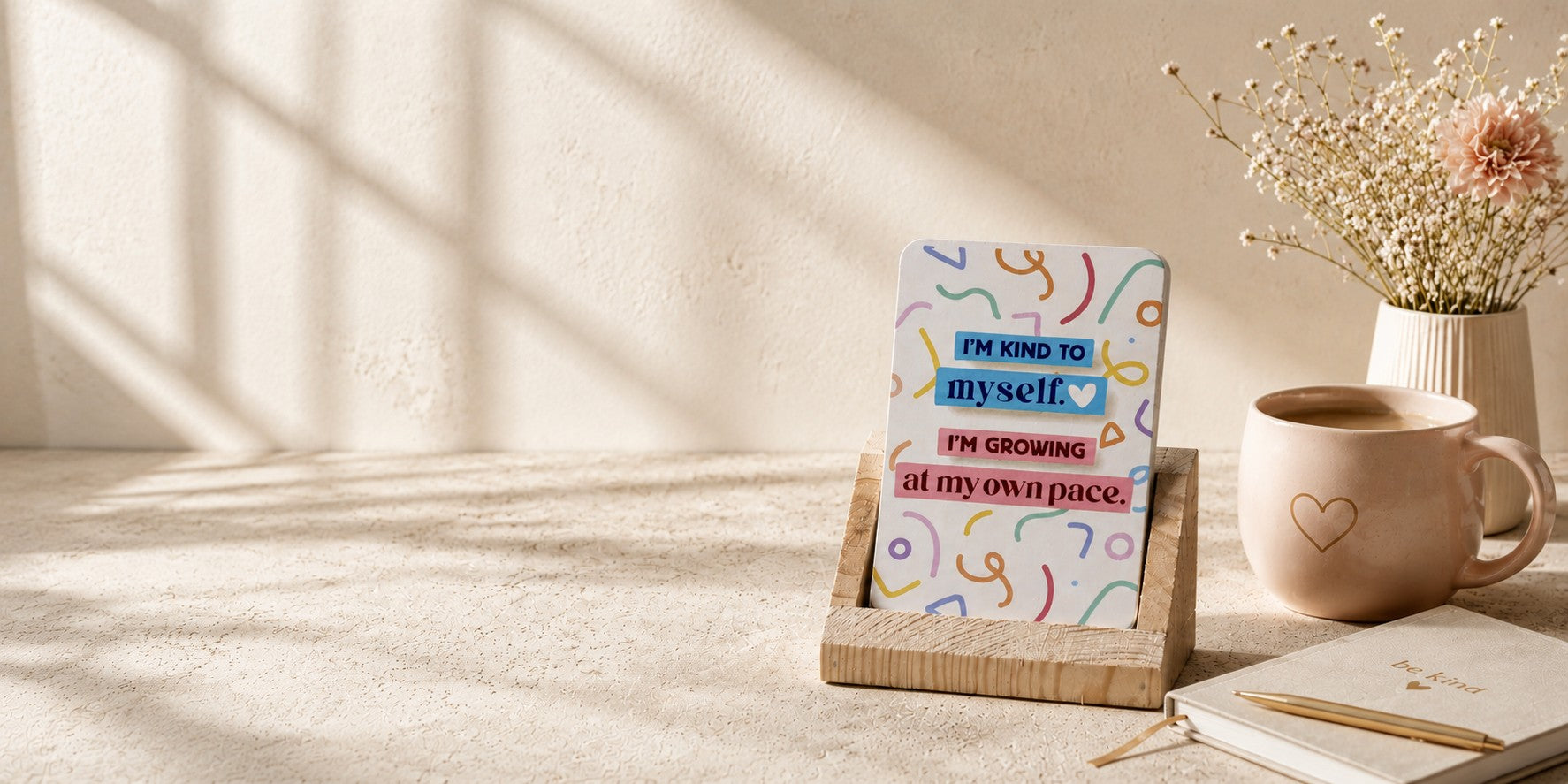 Desk with a motivational card, mug, and notebook in a bright room.