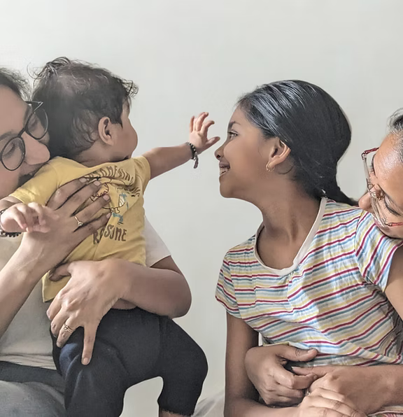 Family of four sitting together on a white background